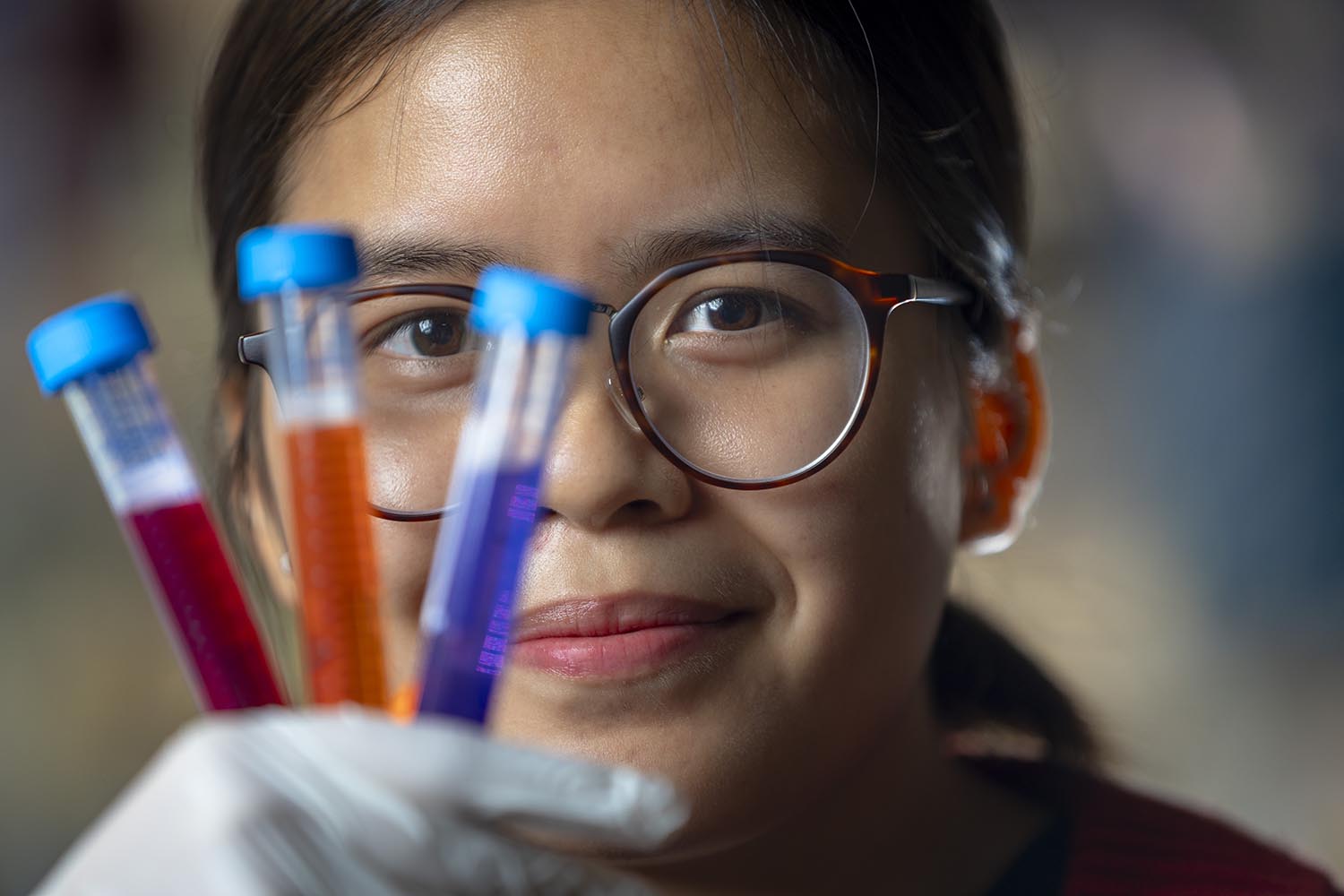 Jackqueline Nguyen holding three test tubes in front of her face.