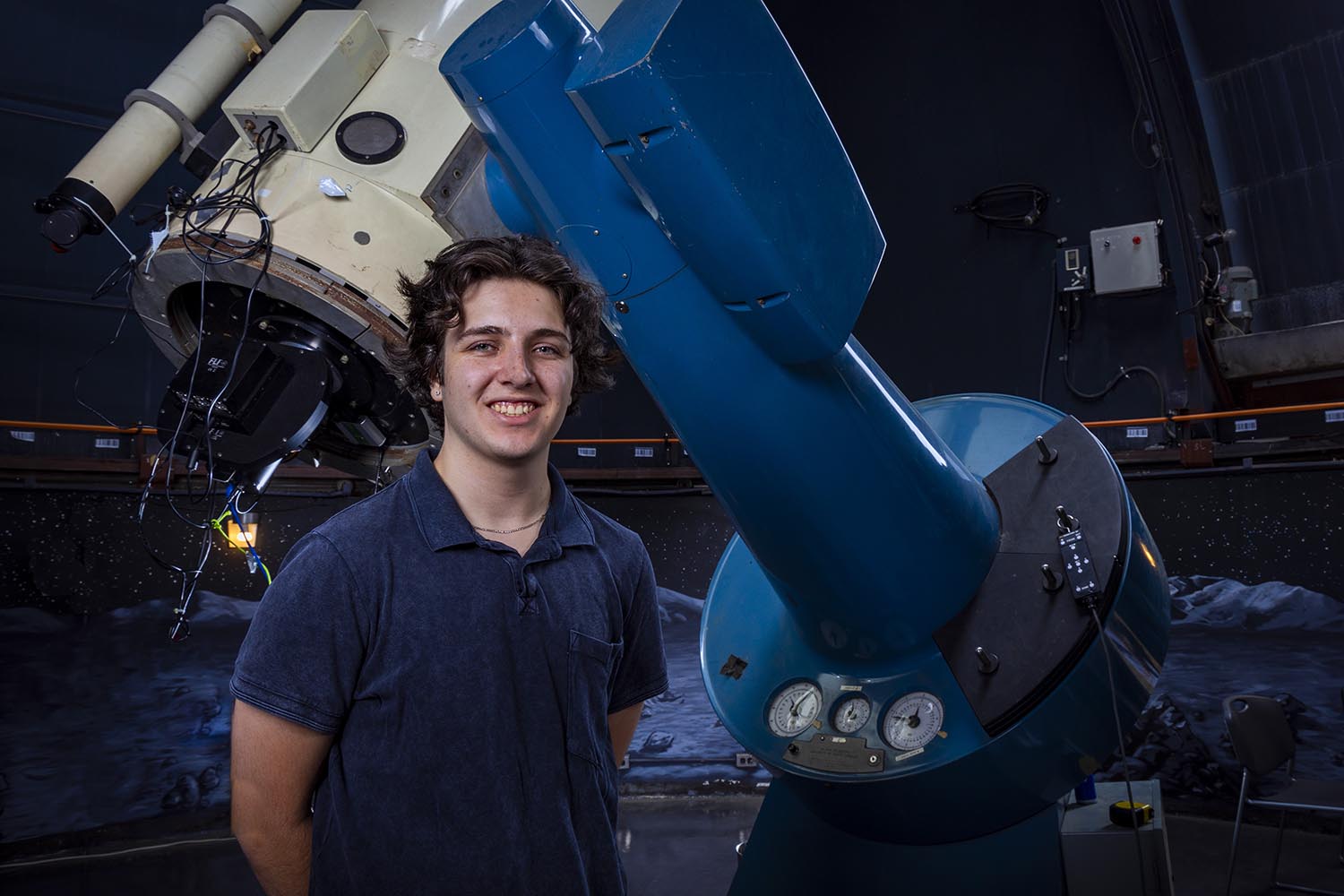 Donovan Schlekat standing in front of a telescope.