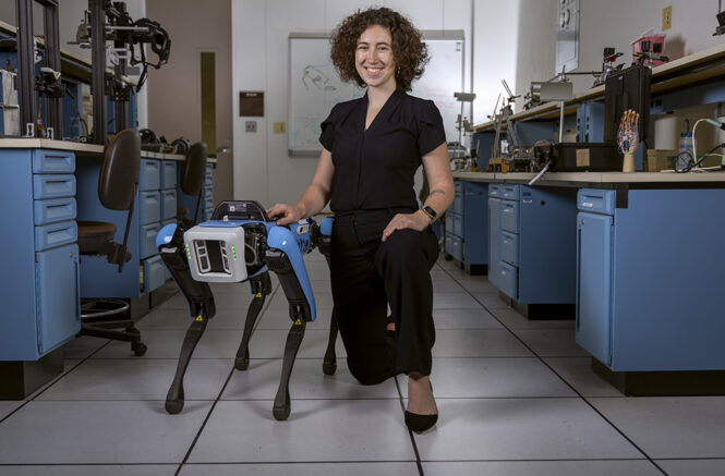 Lilly Nekervis, a senior undergraduate students, majoring in Information and Library Science at UNC-Chapel Hill, poses with a robotic dog in a robotics lab.