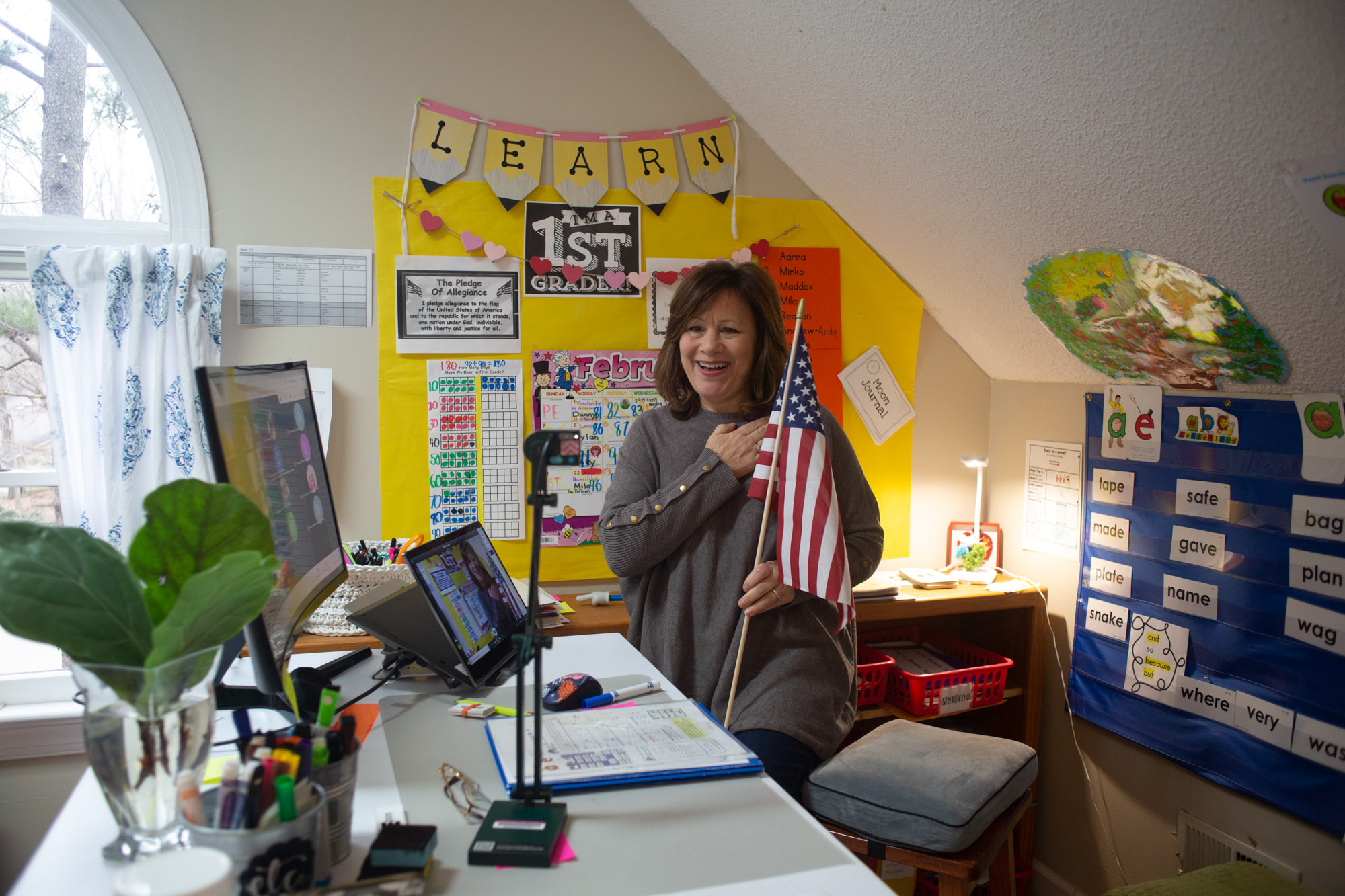 Suzanne Zaccardo holds an American flag in front of her computer to lead her online class in the Pledge of Allegiance