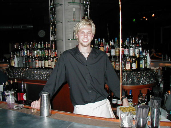 Mike Christian stands behind a bar in the 1990s