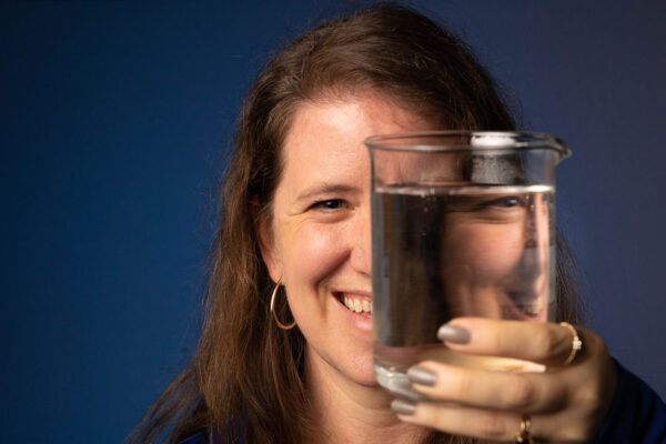 Amanda Thompson holds up a beaker of water in front of her face