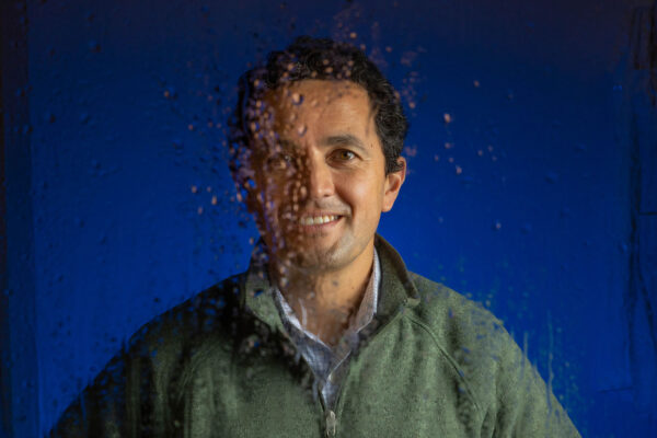 Diego Riveros-Iregui looks through a piece of glass covered in water droplets
