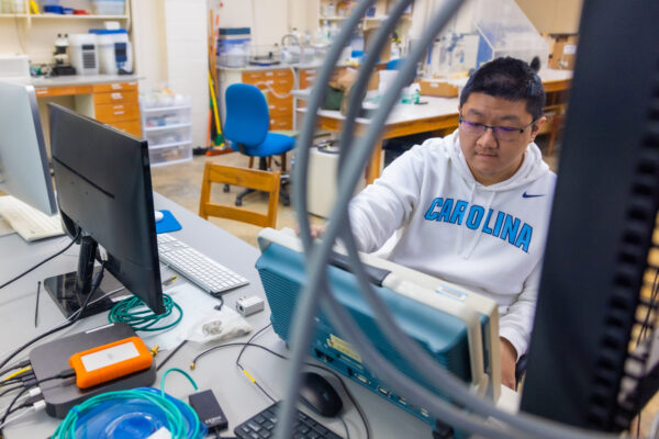 Photo of Aobo Li sitting at the computer in the Gruszko lab.