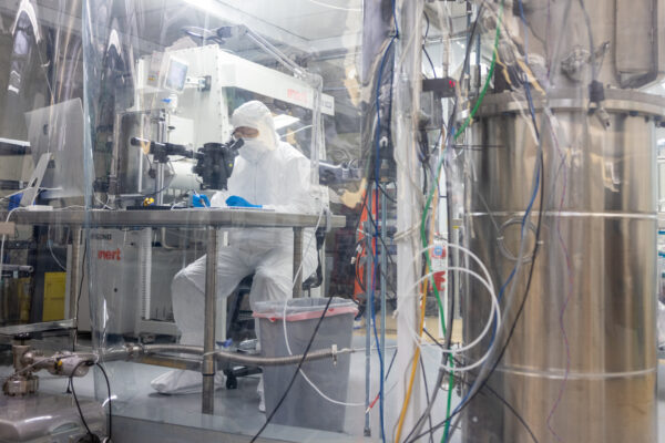 Aobo Li sits in PPE gear and a controlled lab conducting experiments.