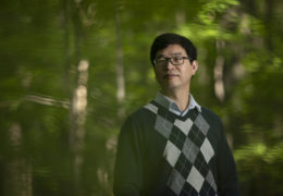 Conghe Song stands for a portrait in a forest.