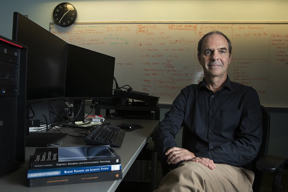 Photo of Dan Anderson seated at a desk in front of a whiteboard.