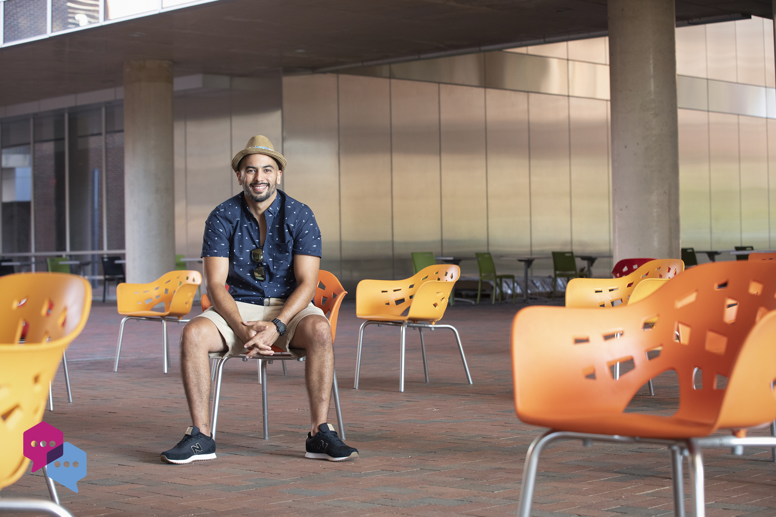 Esteban Agudo sits in a orange chair in the quad of the Genome Sciences Building