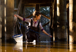Emily Harmon holds a net under a dock at Jordan Lake