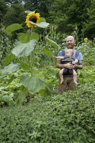 Chad Stevnes Heartwood stands in his garden with son Osha