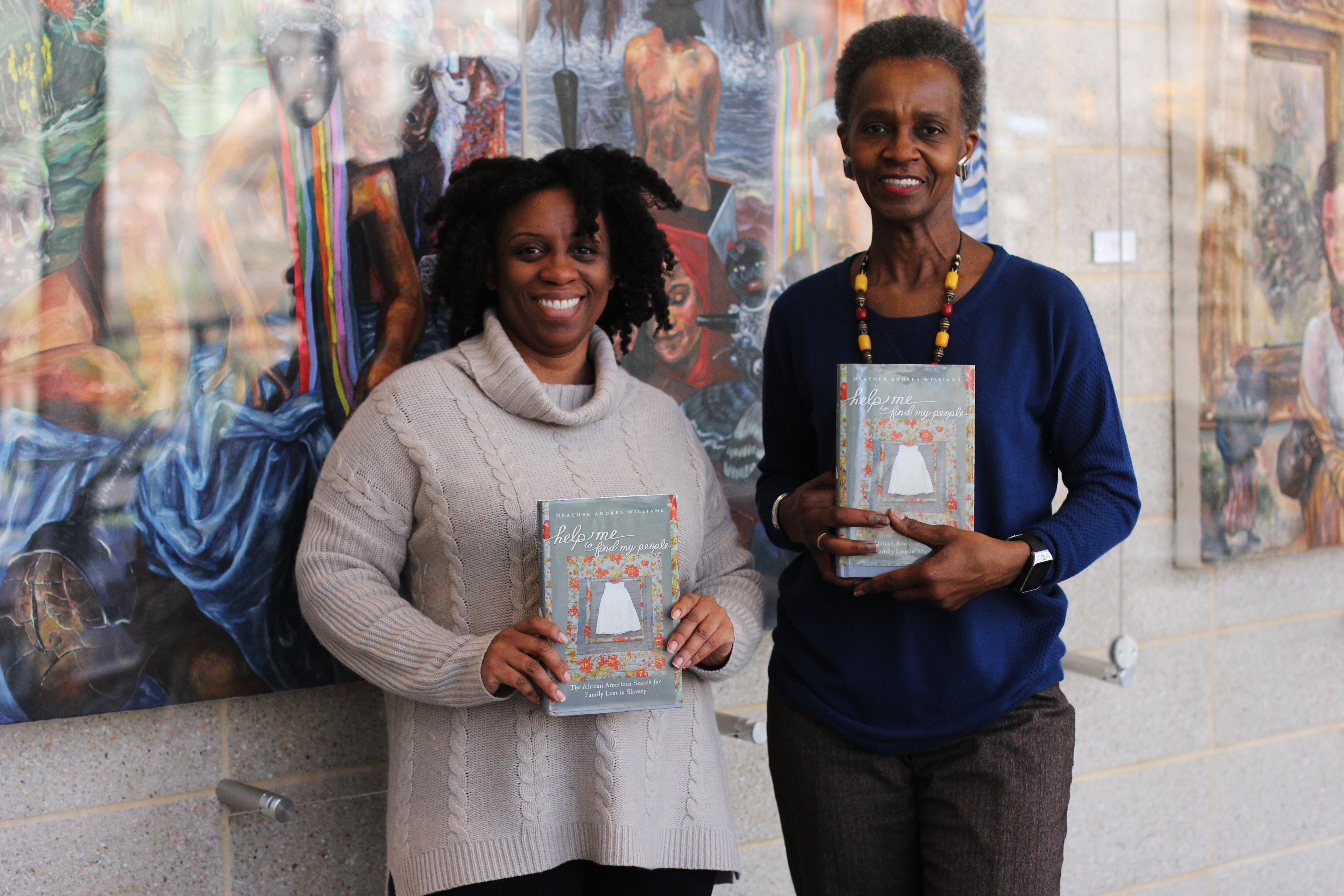 Tanya Shields and Kathy Perkins hold up the book "Help Me to Find My People" by former UNC-Chapel Hill professor, Heather Williams.