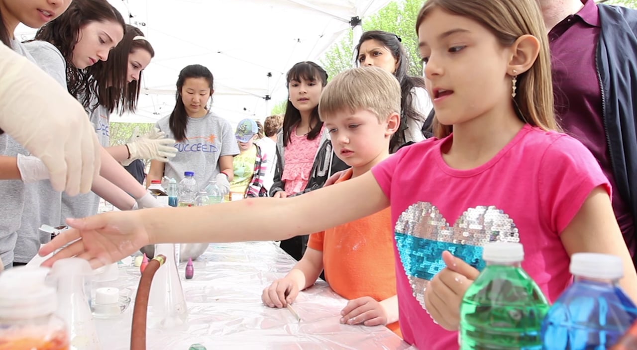 screen grab of kids at the SUCCEED science faire. Click to start video.