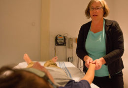 a woman massages the hand of a child lying on a table