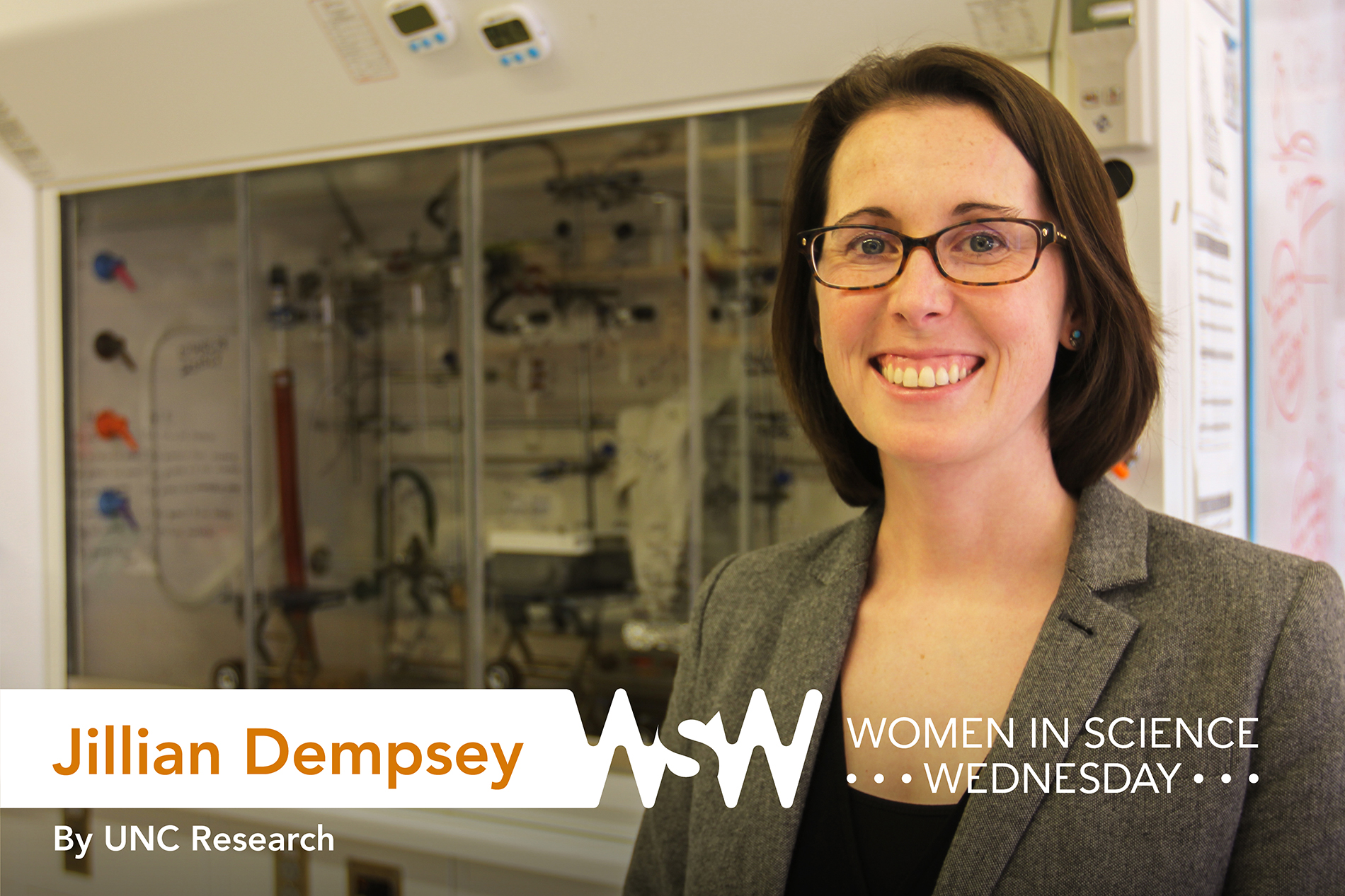 a woman wearing a tan suit stands in a lab