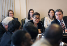 Karen Bass sits at a table surrounded by people