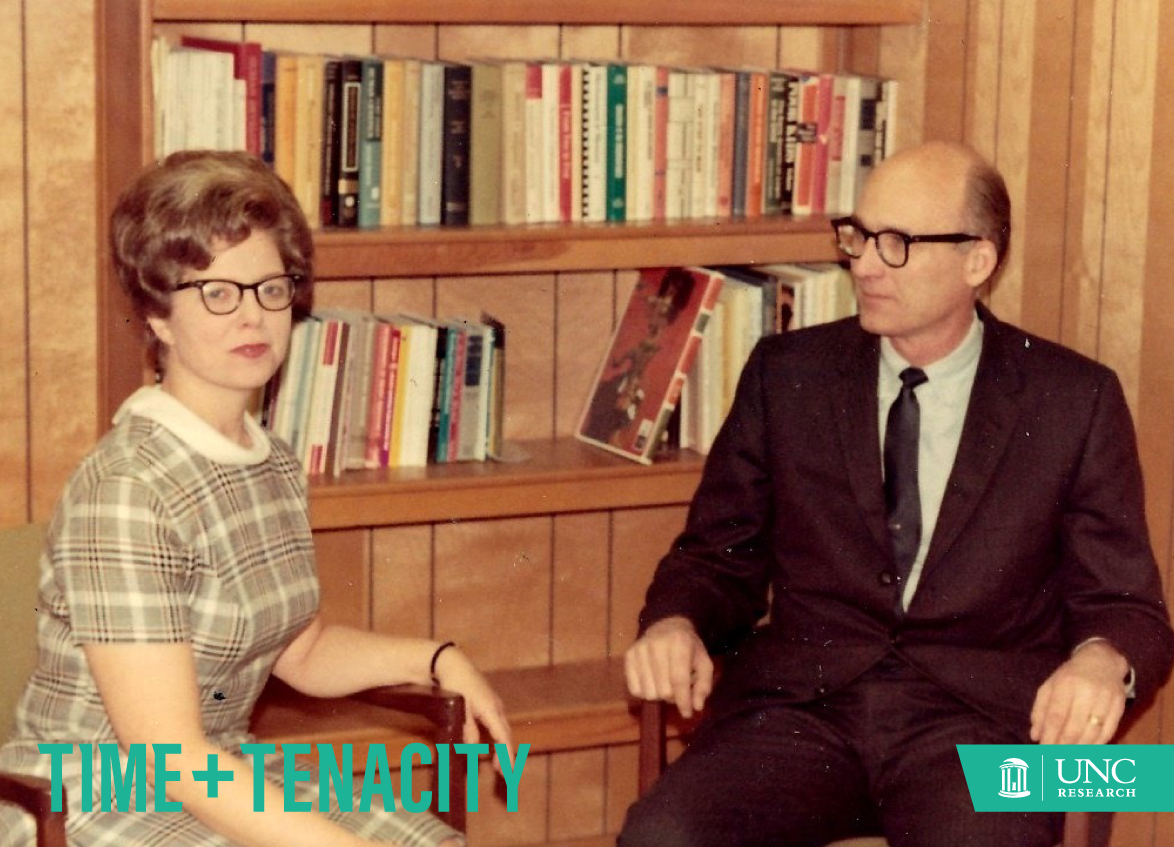 A woman and a man sit in an office type setting in the 1960s.