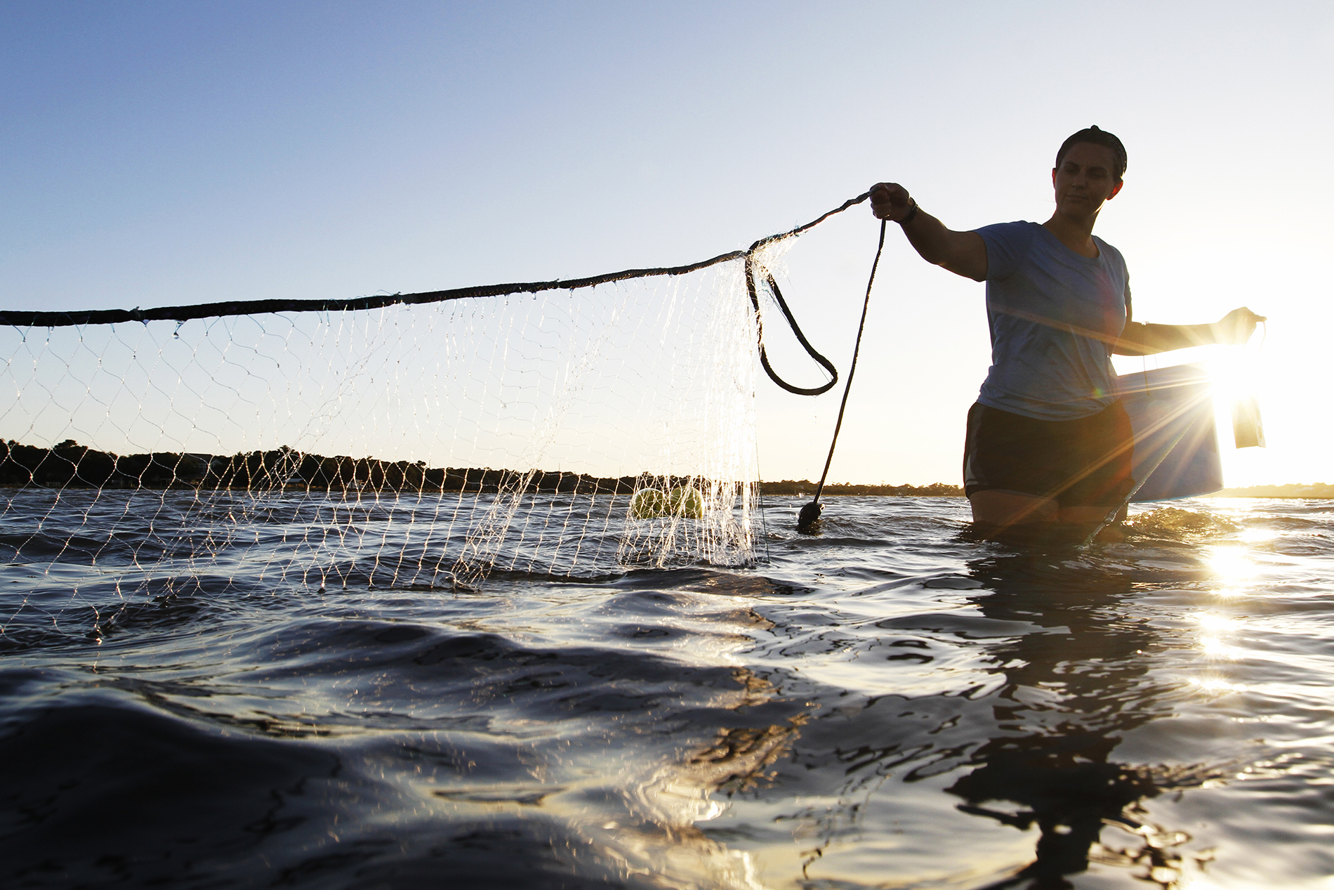 a woman holds a net across thigh-deep water