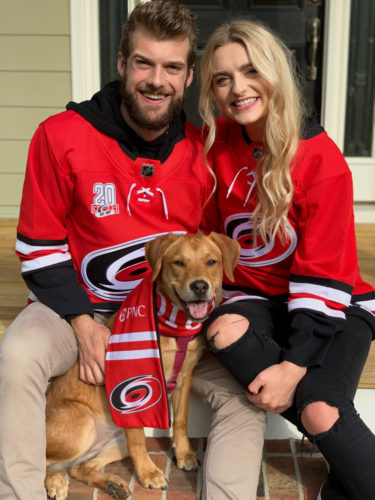 Kevin Pendergast, Makayla Hamrick, and a golden lab wearing Carolina Hurricanes gear