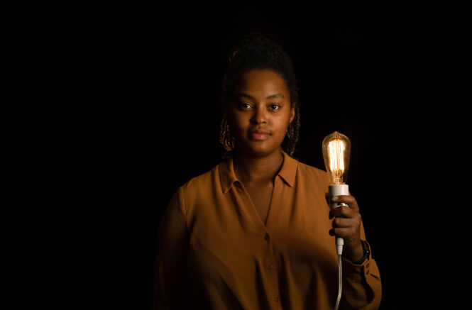 A woman poses for a portrait holding a lightbulb