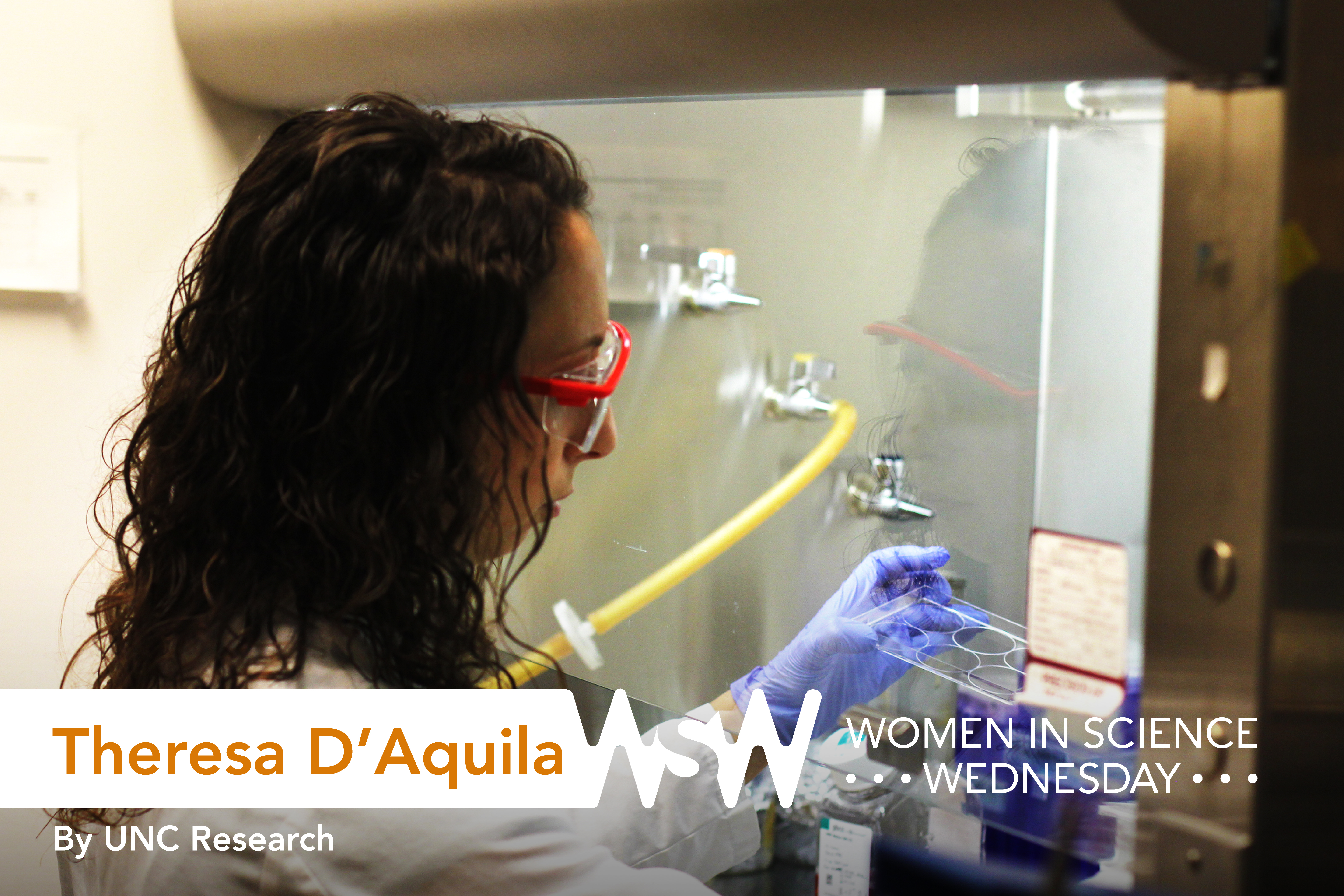 Theresa D'Aquila, wearing protective glasses, a lab coat, and gloves, working in the lab.