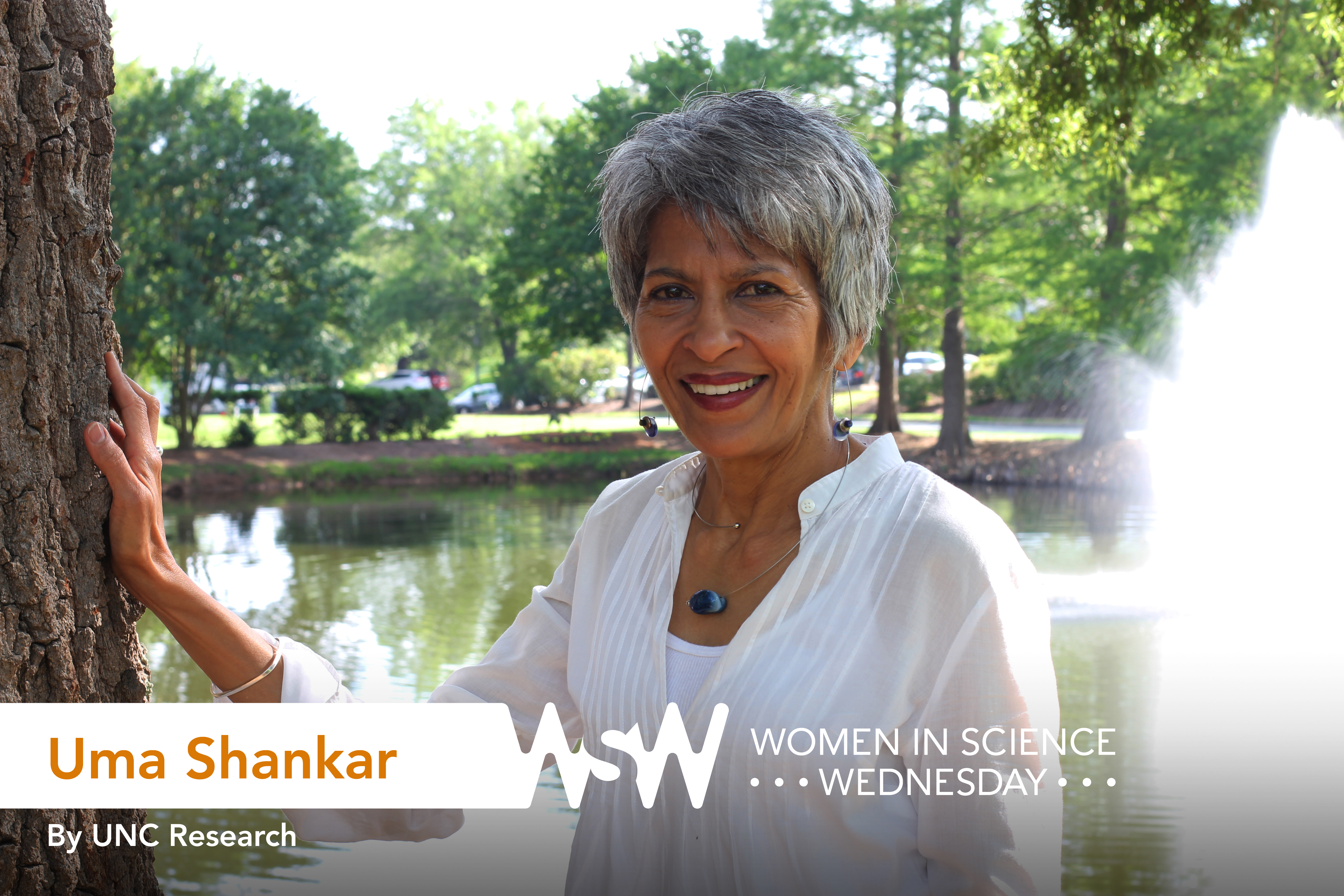 Uma Shankar poses in front of a lake with a fountain on campus