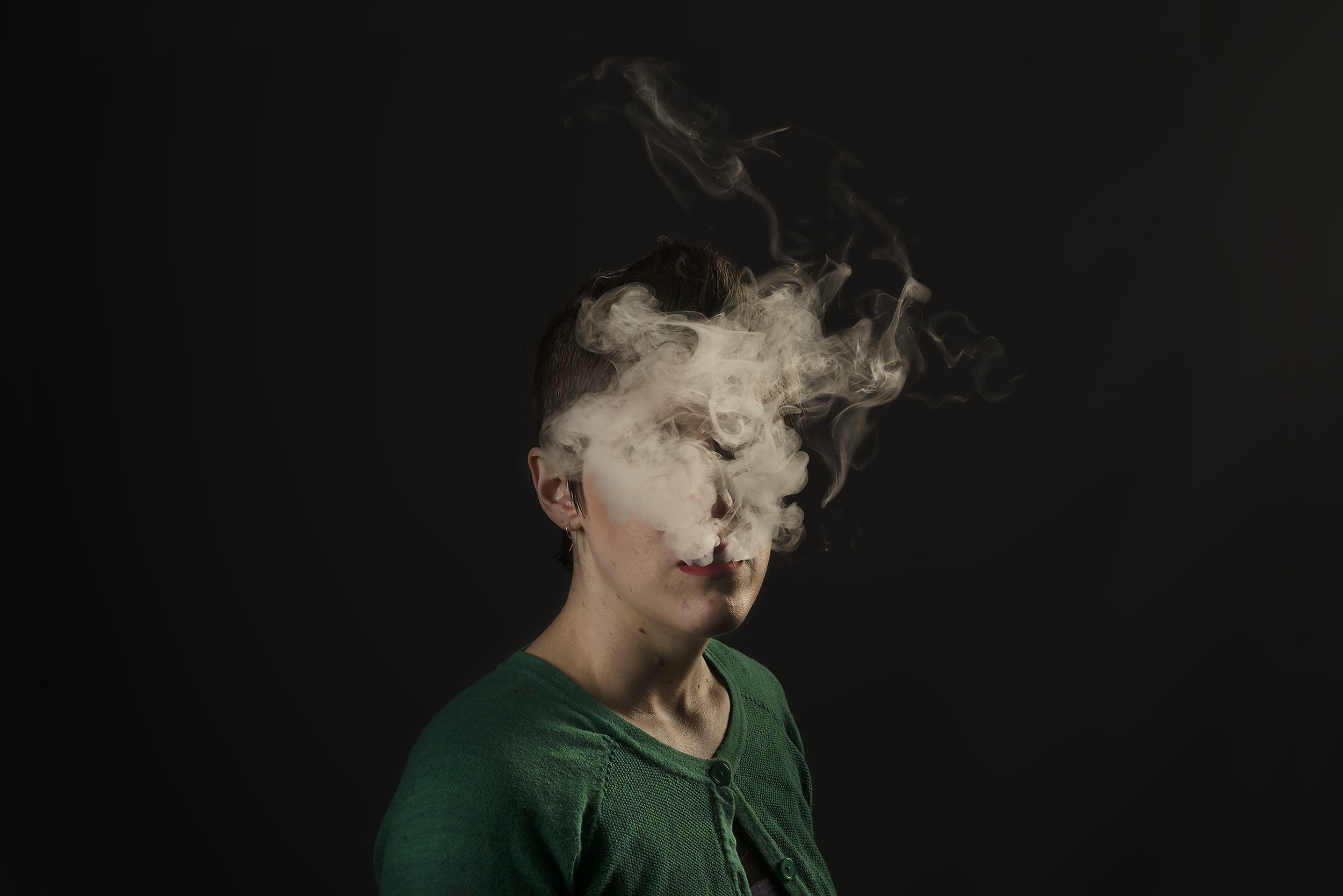 a puff of vapor covers a young woman's face