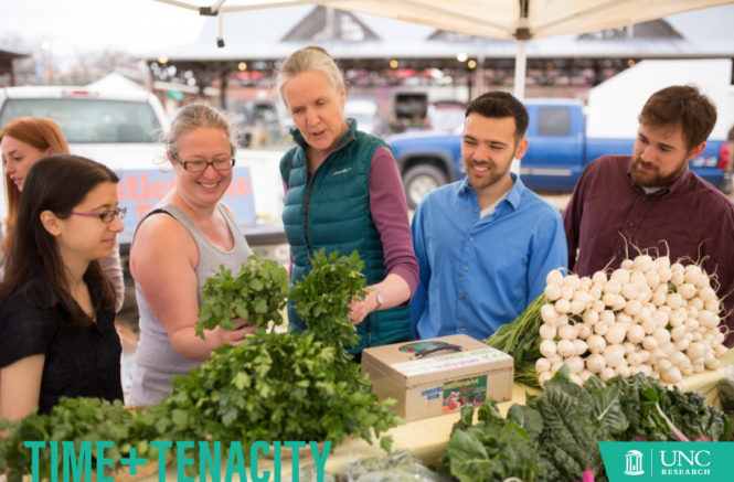 Alice Ammerman looks at cilantro along with four other people at the Carrboro Farmers' Market