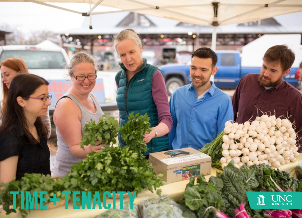 Alice Ammerman looks at cilantro along with four other people at the Carrboro Farmers' Market