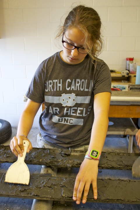 Photo of Anna Atencio smoothing out a sediment core sample on to two long trays in the Rodriguez lab.