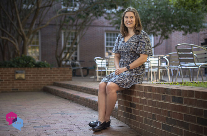 a woman sits on a low wall in a courtyard