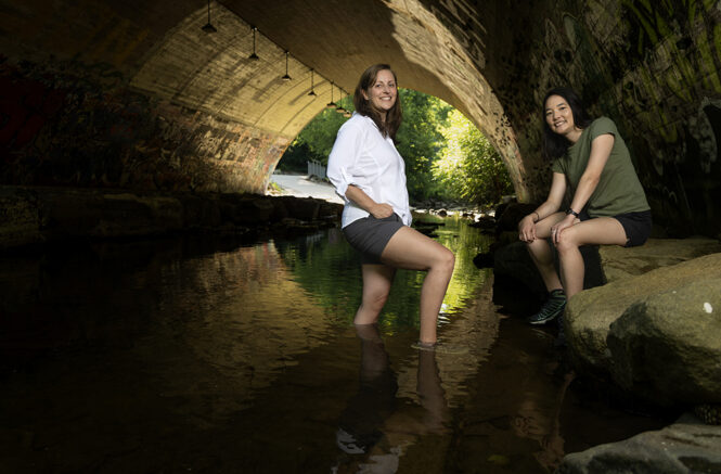 two women stand under a bridge in Bolin Creek