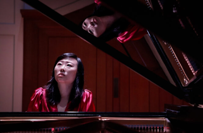a woman playing a grand piano