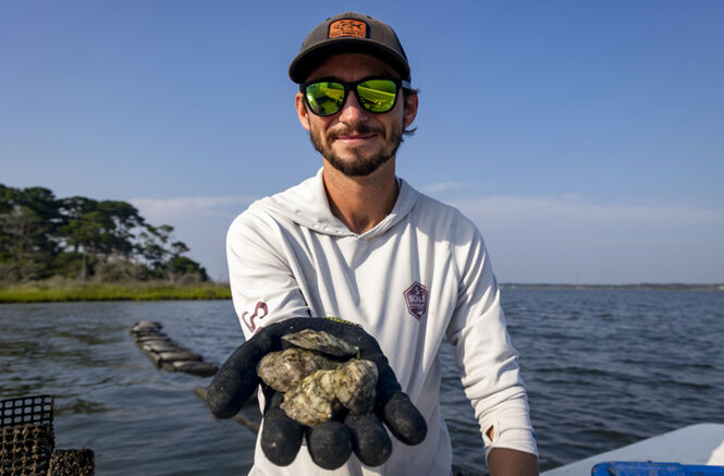 a young man holds a handful of oysters