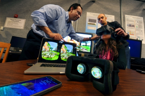 Photo of Dinesh Manocha and Carl Schissler help someone testing out their VR-headphones display.