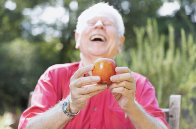 Don Nonini laughs while holding an apple