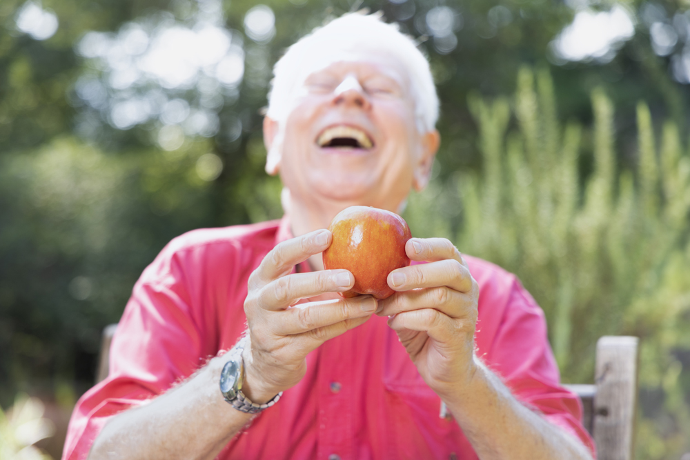 Don Nonini laughs while holding an apple