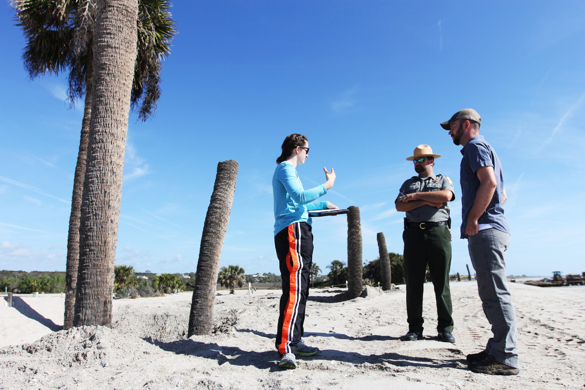 Elsemarie deVries and Joe Lemeris talk to an officer on the beach about their research