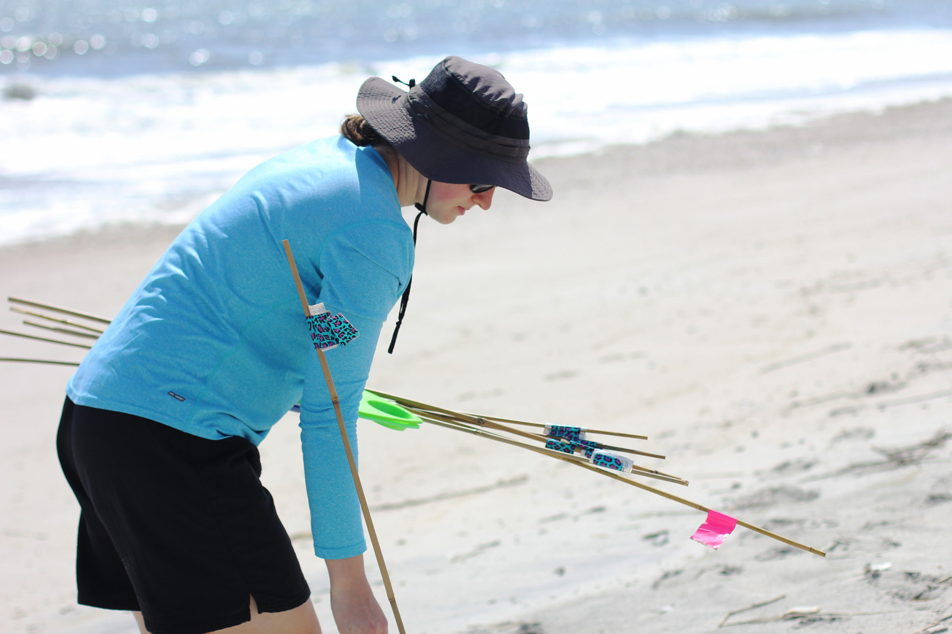 Elsemarie deVries sets up bamboo stakes into the beach