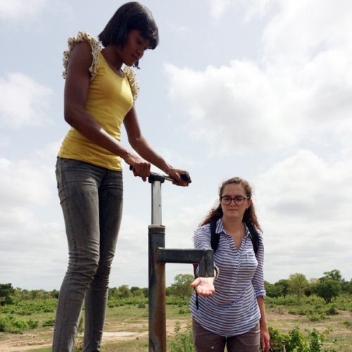 Photo of Emma Kelly holding her hand out of a well in Kpendua, Ghana.