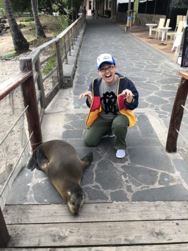 Xiaoming Liu poses next to a seal in the Galapagos