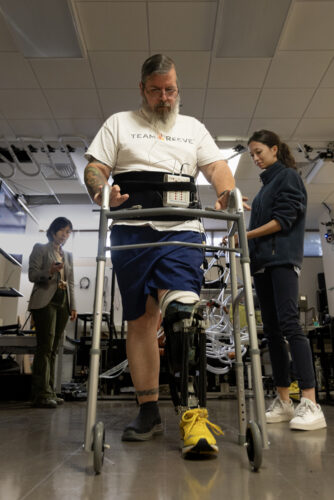 Greg Phillips walks with the prosthetic with assistance from a walker