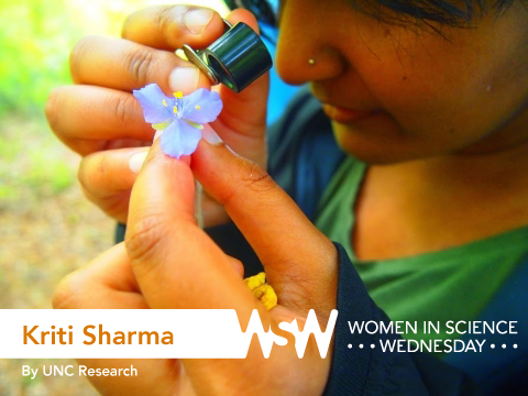 Kriti Sharma examines a purple flower with a magnifying glass