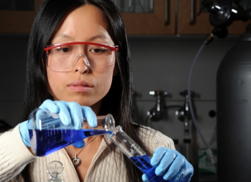 Photo of a female UNC researcher working with test tubes in the lab.