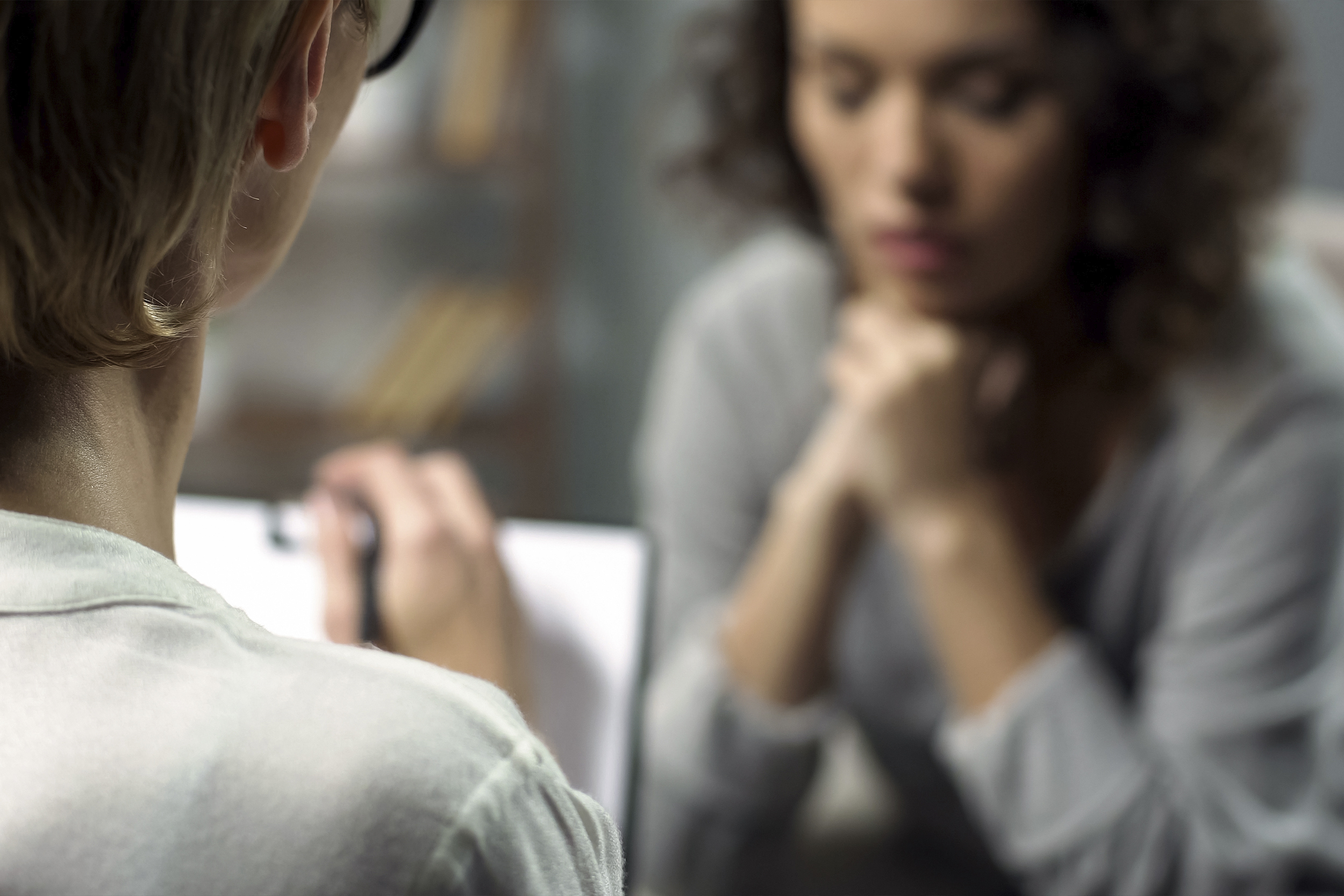 a woman takes notes while another, who looks in distress, shares her thoughts