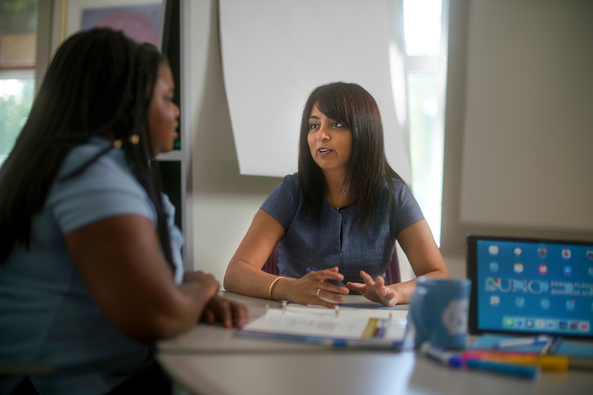 Shimul Melwani sits at a table and has a discussion with Angelica Leigh