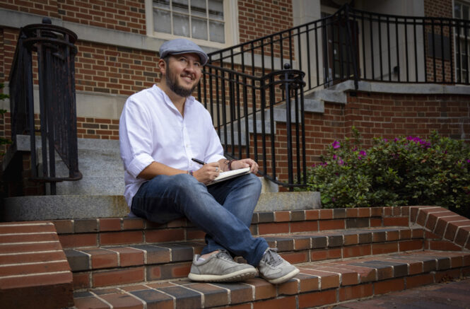 Oswaldo Estrada sits on a brick step while posing for a portrait.