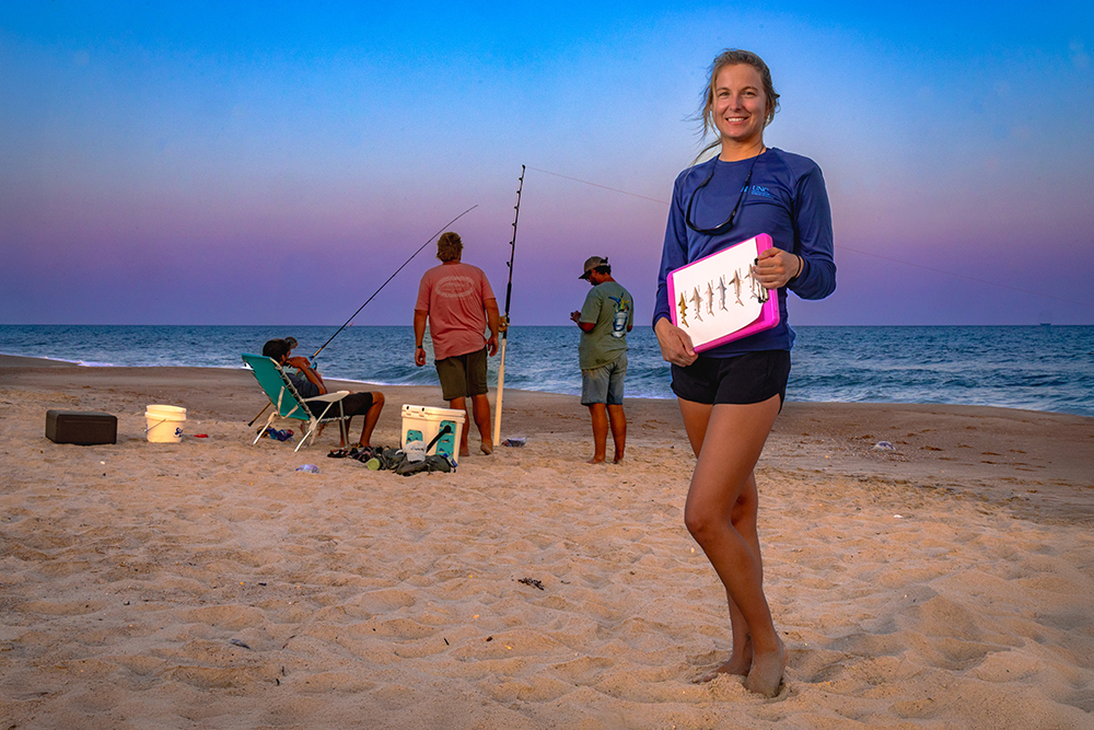 young woman on the beach at sunset with anglers fishing behind her