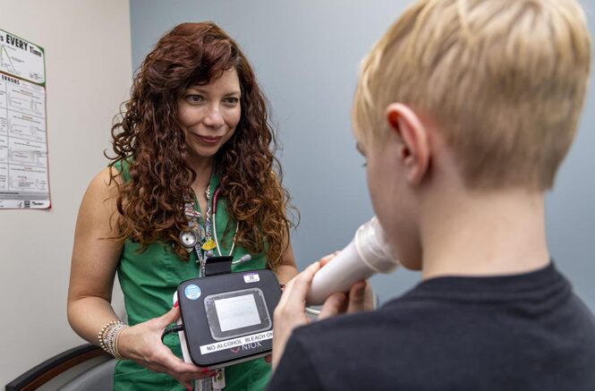 A female doctor administers a breathing test on a male child.