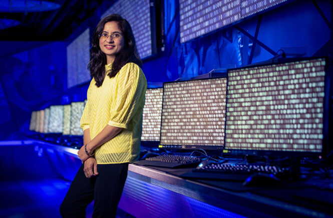 a woman in front of a line of computers covered in code