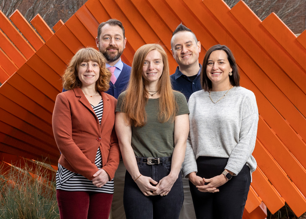 The full-time staff of Endeavors stand in front of an abstract orange statue. Left to right (front): Alyssa LaFaro, Corina Cudebec, Layla Dowdy; left to right (rear): Andrew Russell, Darren Abrecht.